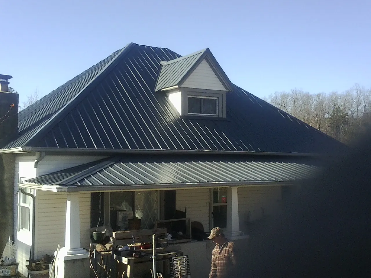 Dark blue standing seam metal roof with a dormer above a front porch in Montpelier